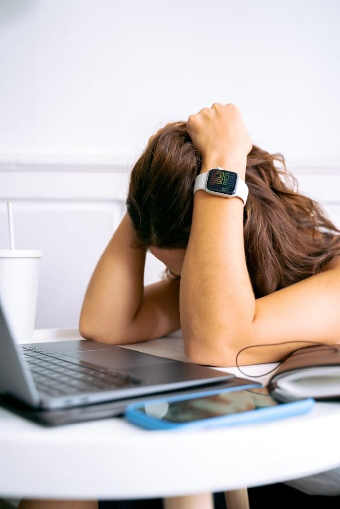 pexels-photo-6173662 A woman looking overwhelmed at a desk with a laptop, symbolizing remote work stress.